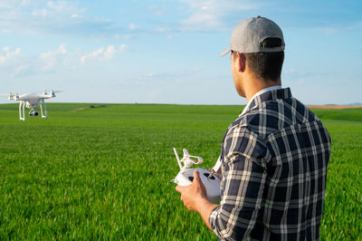 Side view of man standing on field against sky