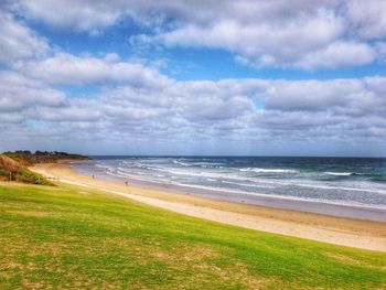 Scenic view of beach against cloudy sky at sunset