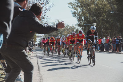 Crowd amidst cyclists riding bicycles on road during competition