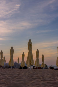 People at beach against sky during sunset