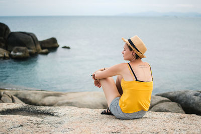 Young woman sitting on rock at beach