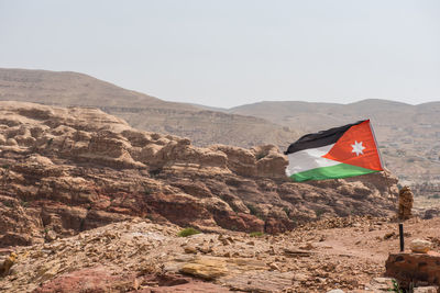 Jordanian flag waving by mountains against clear sky