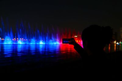 Woman photographing illuminated at music concert