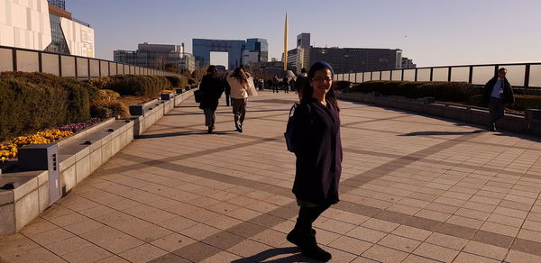 Rear view of people walking on footpath in city