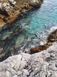 High angle view of turquoise water between rocks
