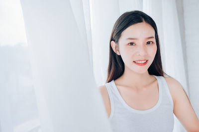 Portrait of a smiling young woman standing at home