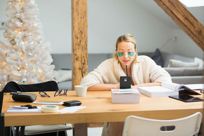 Businesswoman working at home by christmas tree