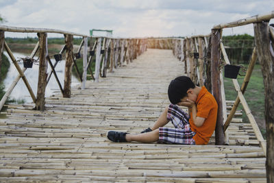 Side view of boy sitting on wooden floor