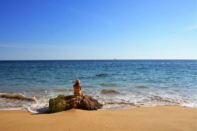 Rear view of woman sitting on beach