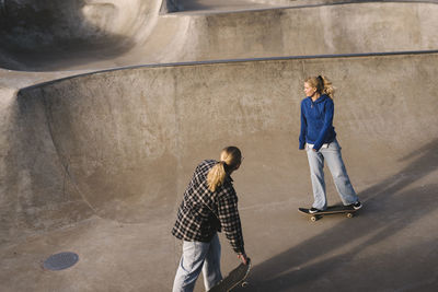 Teenage girls skateboarding in skatepark