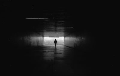 Silhouette person walking in illuminated tunnel