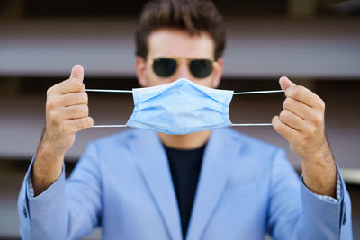 Portrait of businessman holding flu mask standing outdoors