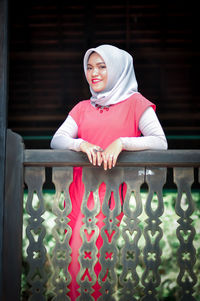 Portrait of young woman sitting on railing