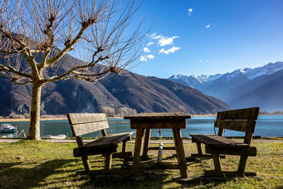 Chairs and tables on snow covered mountains against sky