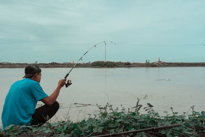 Rear view of man fishing rod