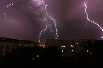 Lightning over illuminated buildings in city at night