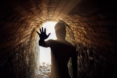 Silhouette person standing in tunnel