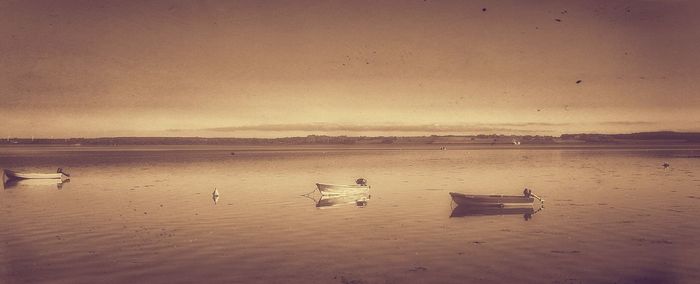 Boats in sea at sunset