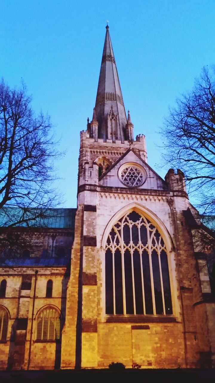 architecture, building exterior, built structure, church, place of worship, religion, spirituality, low angle view, bare tree, clear sky, tree, blue, cross, cathedral, facade, tower, sky, branch