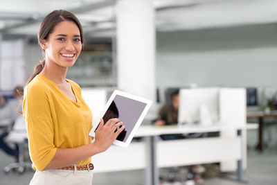 Portrait of smiling businesswoman with digital tablet in office