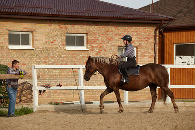 Girl rides a horse and smiles at dad - family leisure outdoors