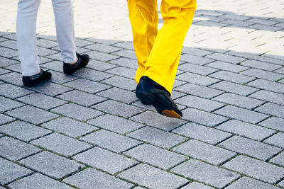 Low section of friends walking on footpath