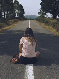 Rear view of boy sitting on road