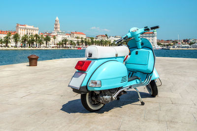 Blue retro scooter is parked in a city near the sea with a helmet. blue vintage scooter stands 