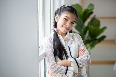 Portrait of smiling young woman standing against wall