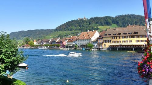 Buildings by sea against clear sky