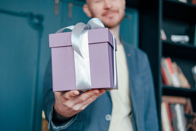 Midsection of man giving gift at home