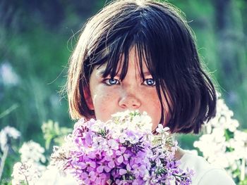 Close-up portrait of girl holding flowers at park