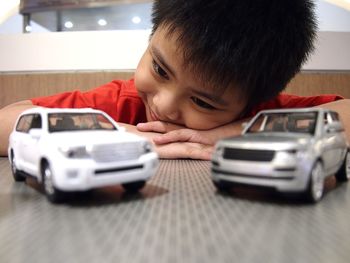 Smiling boy looking at toy cars on table