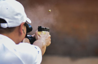 Rear view of man shooting target with handgun