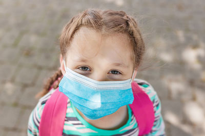 Close-up portrait of a school-age girl with a protective medical mask on her face. new school year 