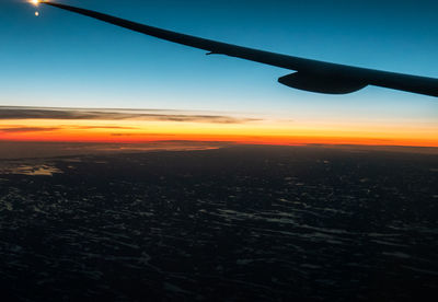 Close-up of airplane wing against sky during sunset