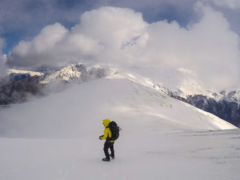 Full length of man on snowcapped mountain against cloudy sky