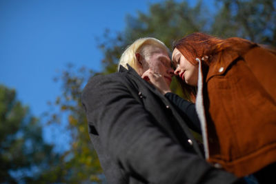 Low angle view of couple embracing against sky