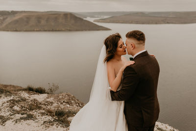 Side view of couple standing at beach