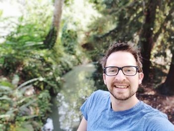 Portrait of smiling young man standing in forest