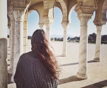 Rear view of woman standing in colonnade