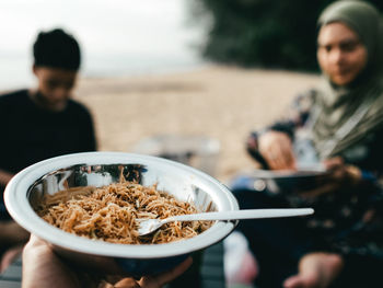 Cropped hand of man holding fried noodles on the beach
