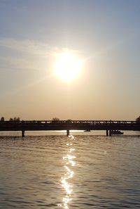 Silhouette bridge over river against sky during sunset