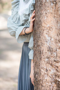 Midsection of woman holding tree trunk