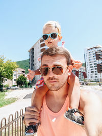 Portrait of father with baby on shoulder outdoors