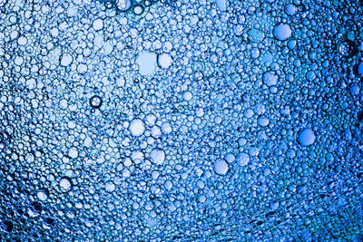 Full frame shot of wet glass against blue background
