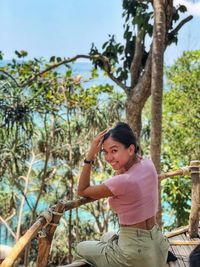 Portrait of woman sitting on tree trunk