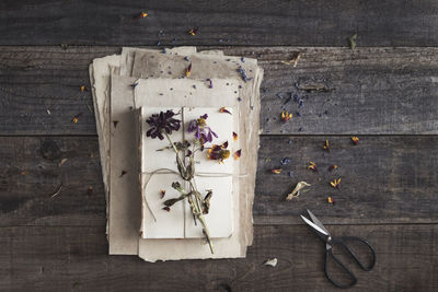 Paper and book layers with scattered dried flowers, petals and scissor