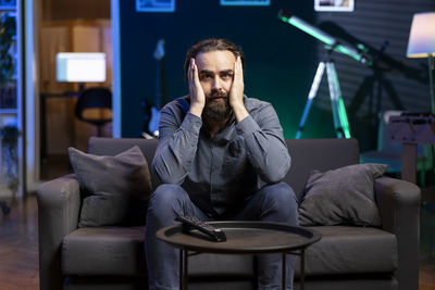 Young man using mobile phone while sitting on sofa at home