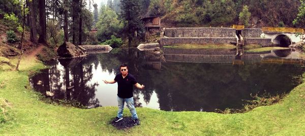 Full length of man standing by waterfall in forest